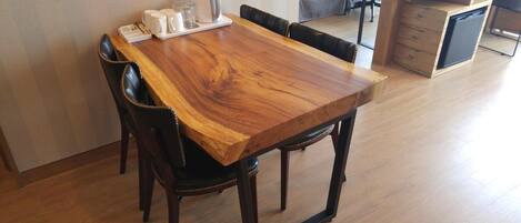 Una mesa de comedor con sillas, una cafetera y una bandeja con tazas y vasos.