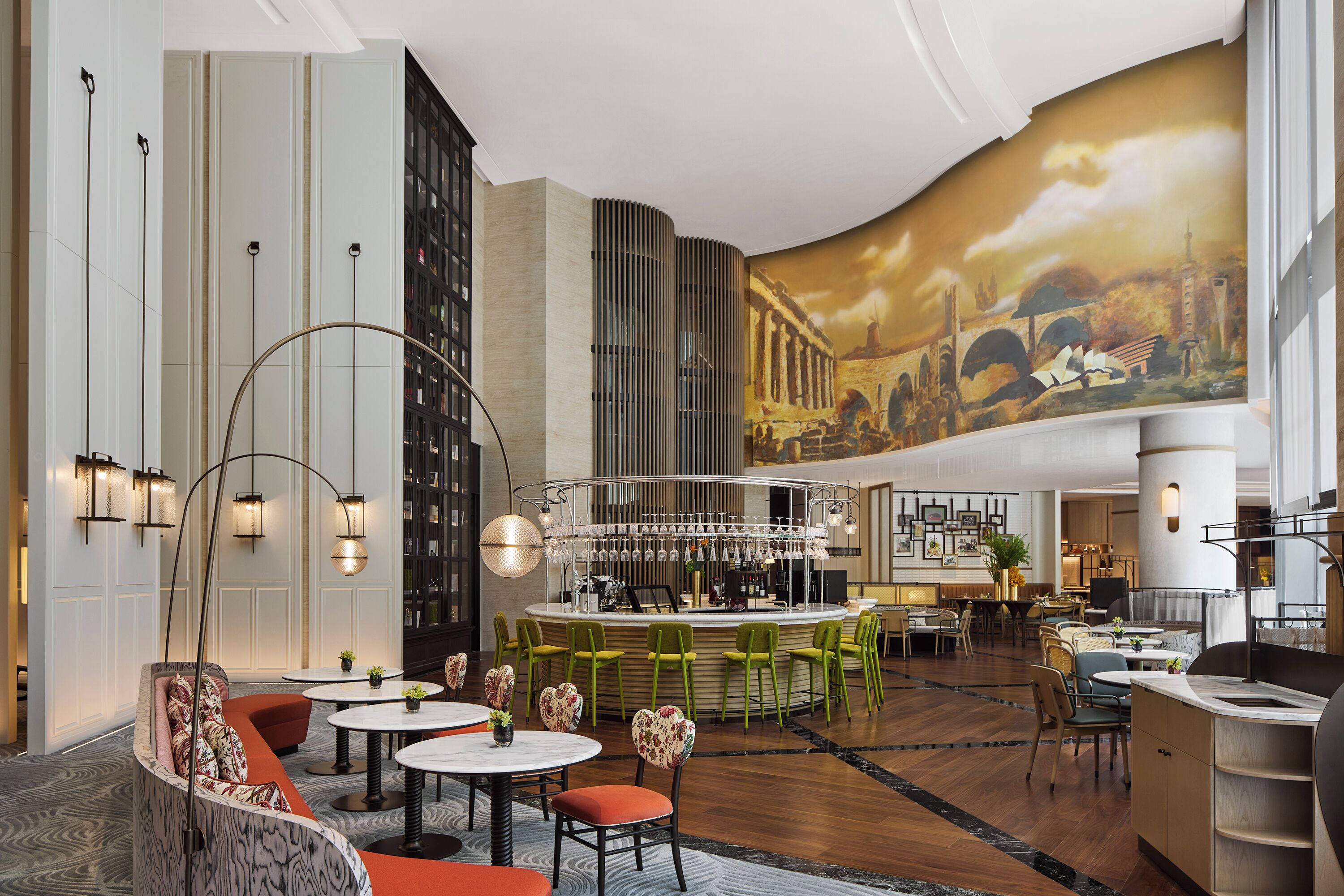 A modern hotel lobby with a bar area, seating arrangements, and a mural on the wall.