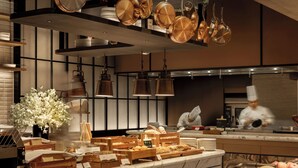 Una cocina moderna con utensilios de cobre colgando del techo, cestas de madera para pan y una encimera de mármol.