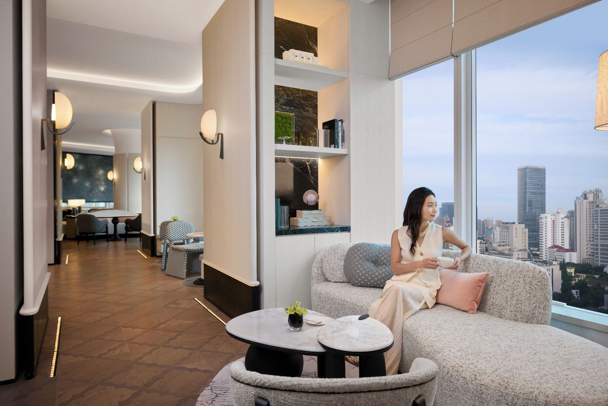 Un moderno vestíbulo de hotel con zona de estar, comedor y un amplio ventanal con vista a la ciudad.