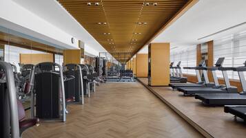 A gym with exercise equipment, mirrored walls, and a wooden floor.