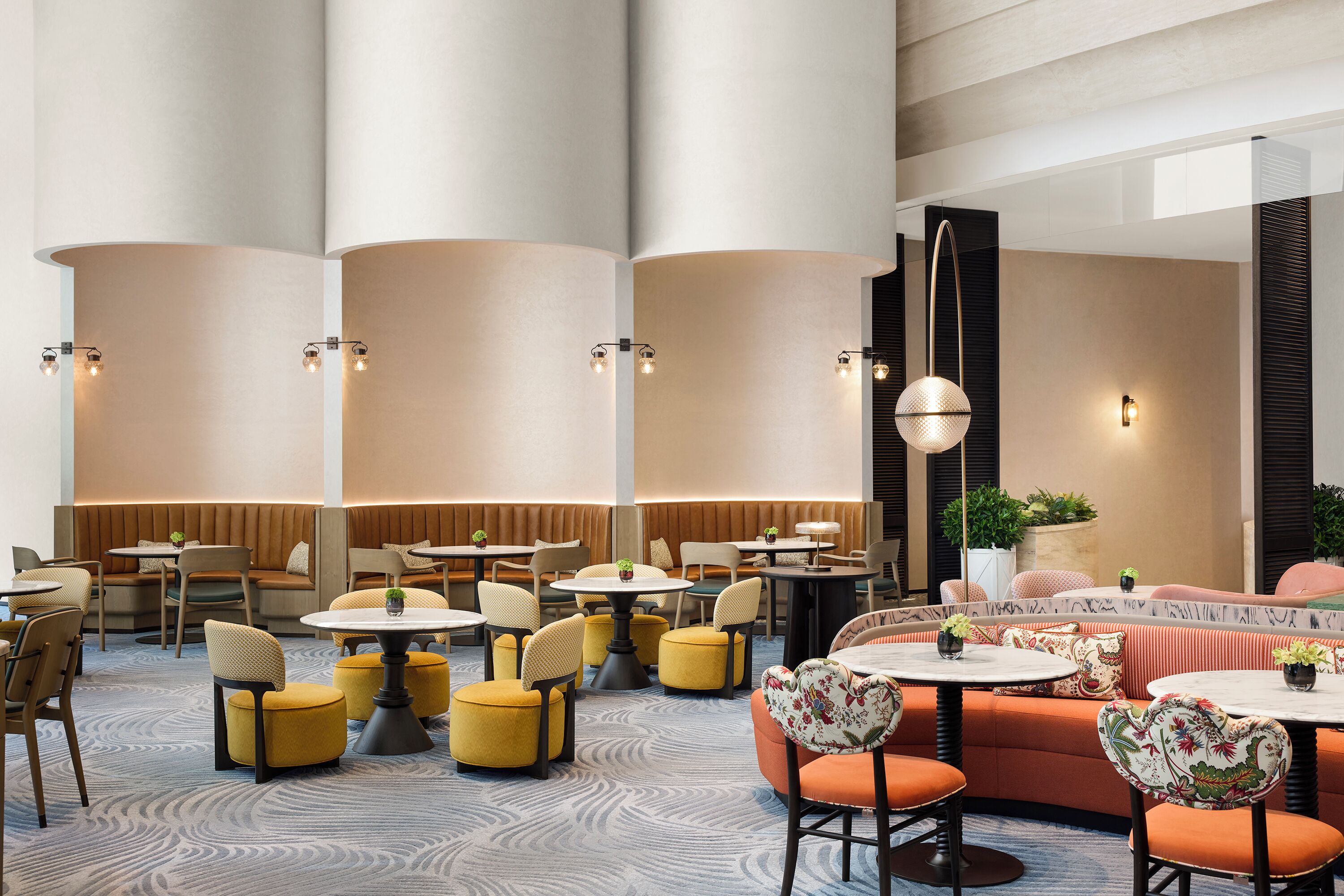 A modern hotel lobby with round tables, cushioned seating, and ambient lighting.