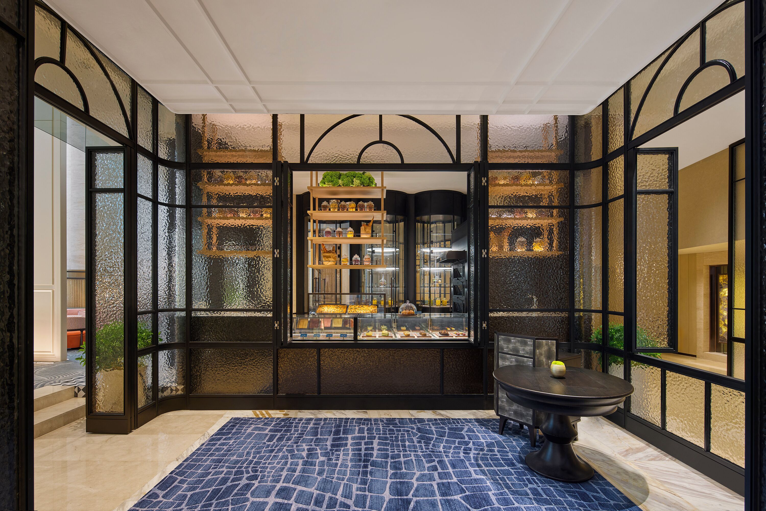 A boutique hotel's interior with a central display case, a round table, and a patterned floor.