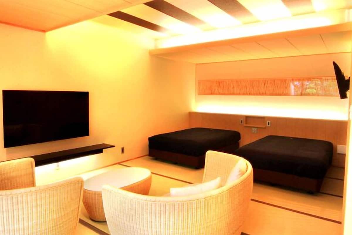 Une chambre moderne équipée d’un téléviseur à écran plat, de deux canapés et d’une petite table ronde.