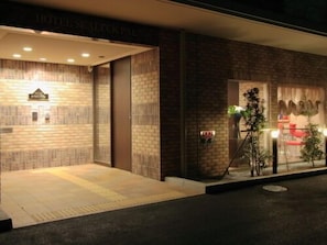L’entrée d’un hôtel, avec une façade en briques et une enseigne au-dessus de la porte.
