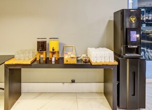 A coffee station with a coffee machine, cups, and a small display.