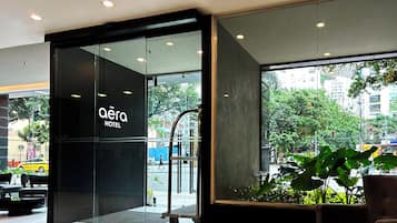A hotel entrance with a glass door, a sign reading 'aera HOTEL', and a view of the street outside.
