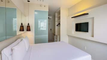 Una habitación de hotel moderna con una cama, un televisor montado en la pared y un espejo que refleja el espacio.
