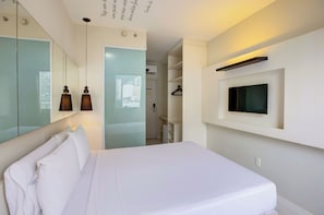 Una habitación de hotel moderna con una cama, un televisor montado en la pared y un espejo que refleja el espacio.