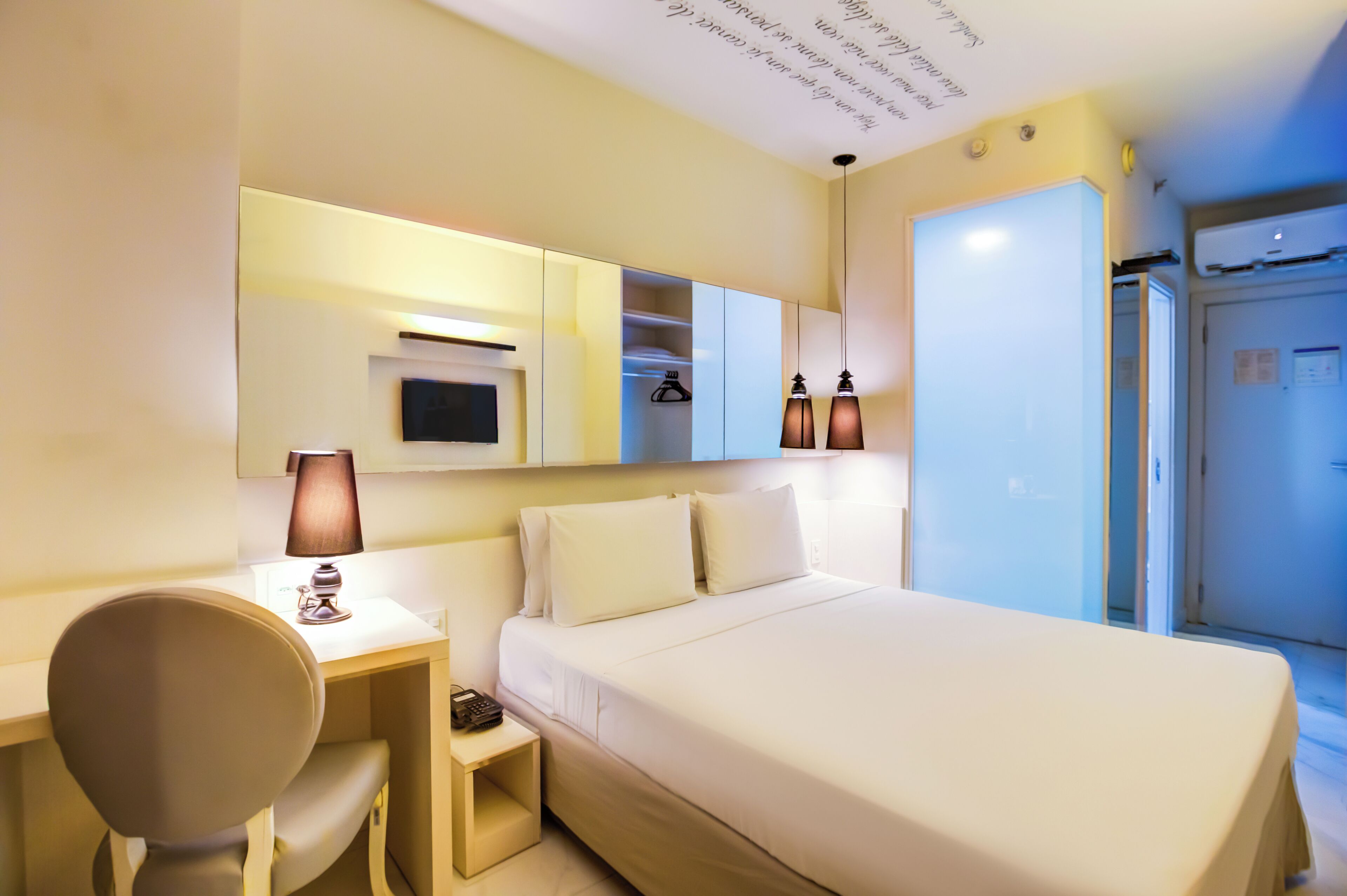 Ein Hotelzimmer mit einem Bett, einem Schreibtisch, einem Sessel, einem Fernseher und einem Kleiderschrank.
