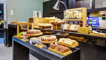 A buffet with various food items, including bread, pastries, and a cake.