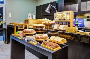 A buffet with various food items, including bread, pastries, and a cake.
