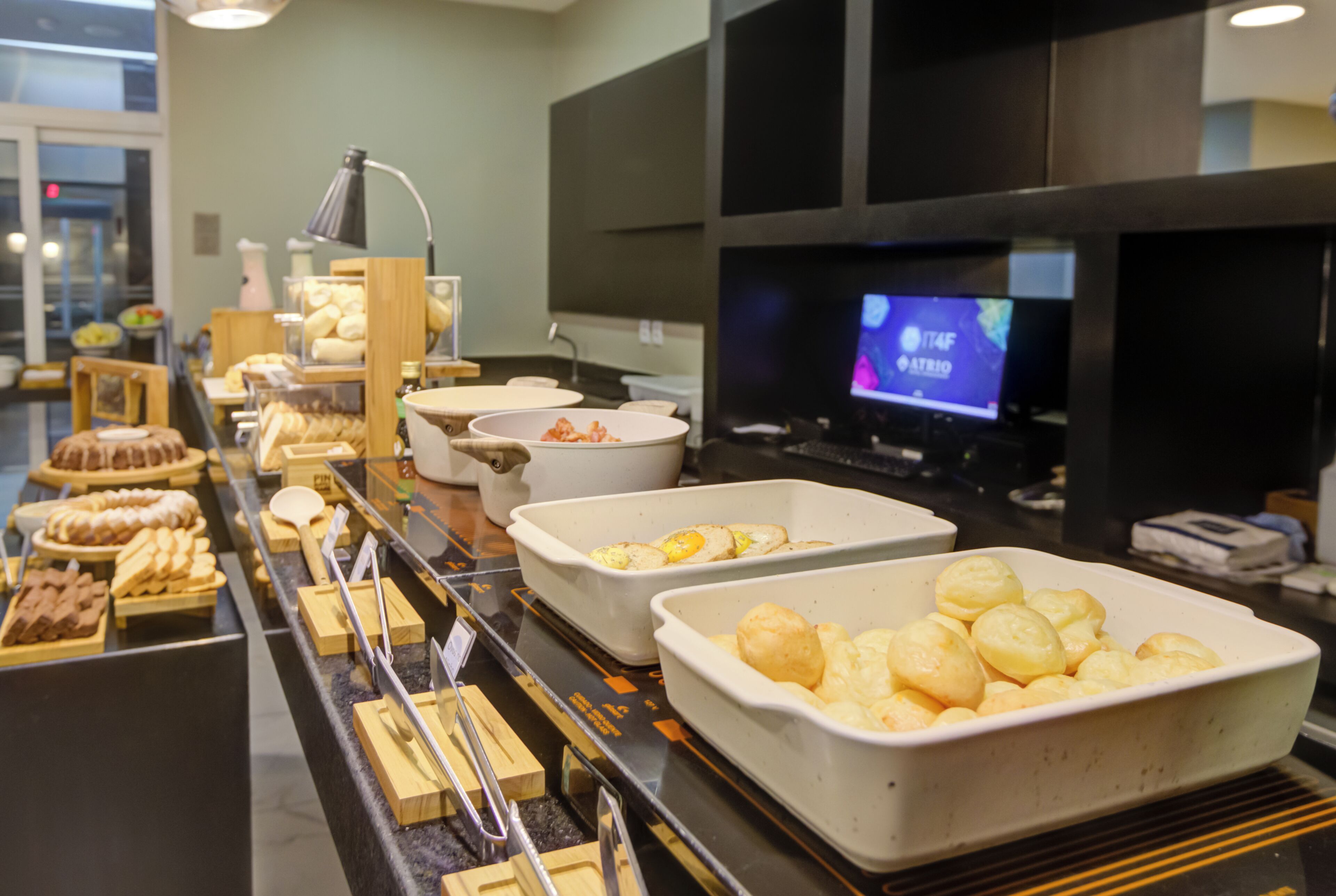 A buffet with various food items and a television screen in the background.