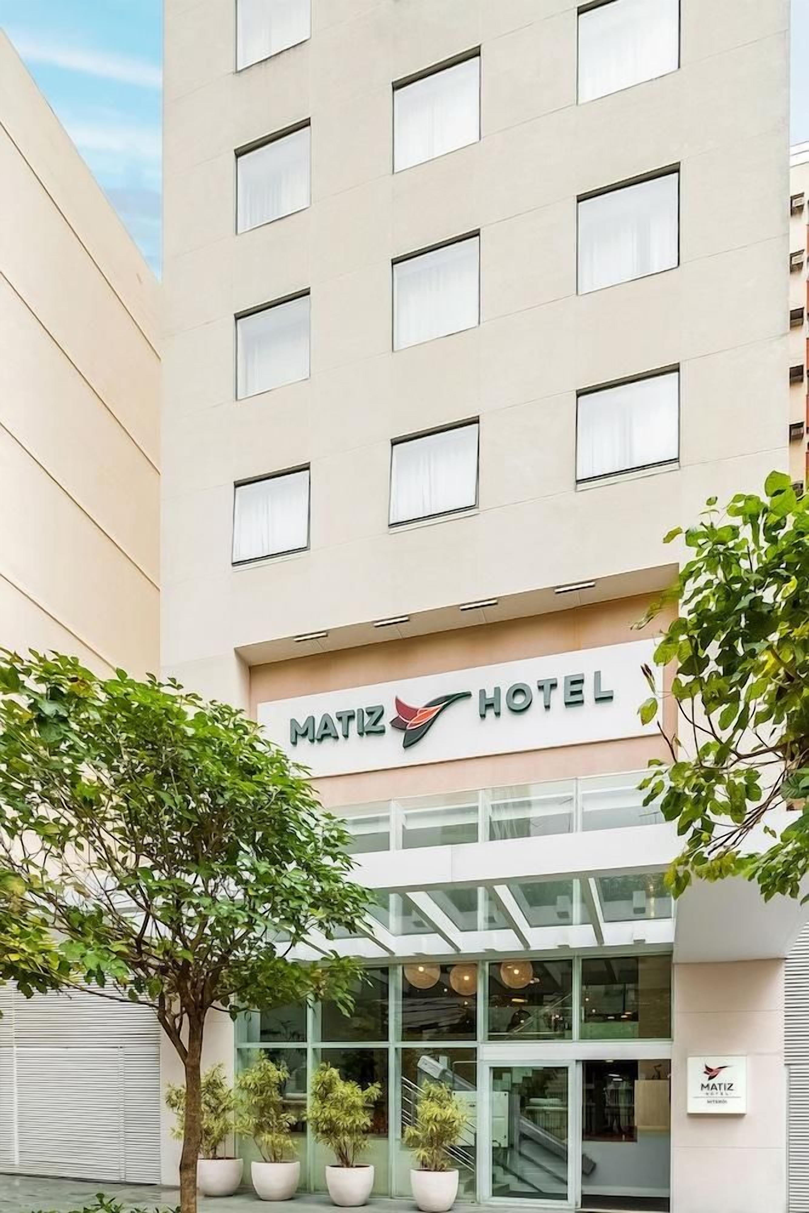 Un moderno edificio de hotel con un letrero que dice 'MATIZ HOTEL' y una entrada de vidrio.