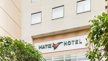 Un moderno edificio de hotel con un letrero que dice 'MATIZ HOTEL' y una entrada de vidrio.