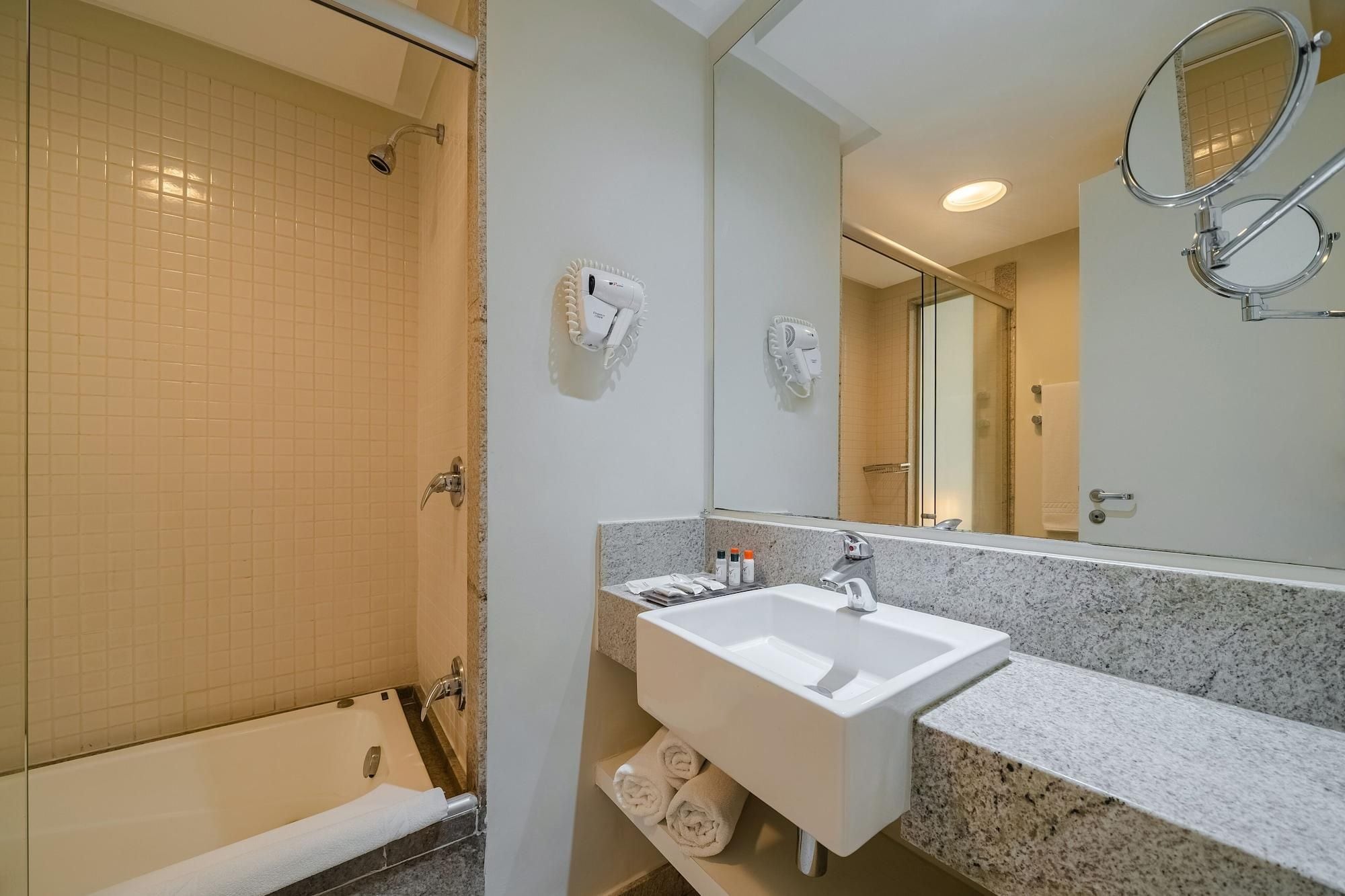 A bathroom with a bathtub, a sink, a mirror, and a shower.