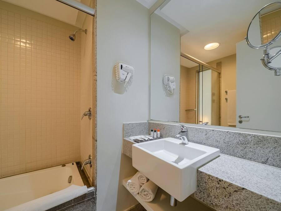 A bathroom with a bathtub, a sink, a mirror, and a shower.