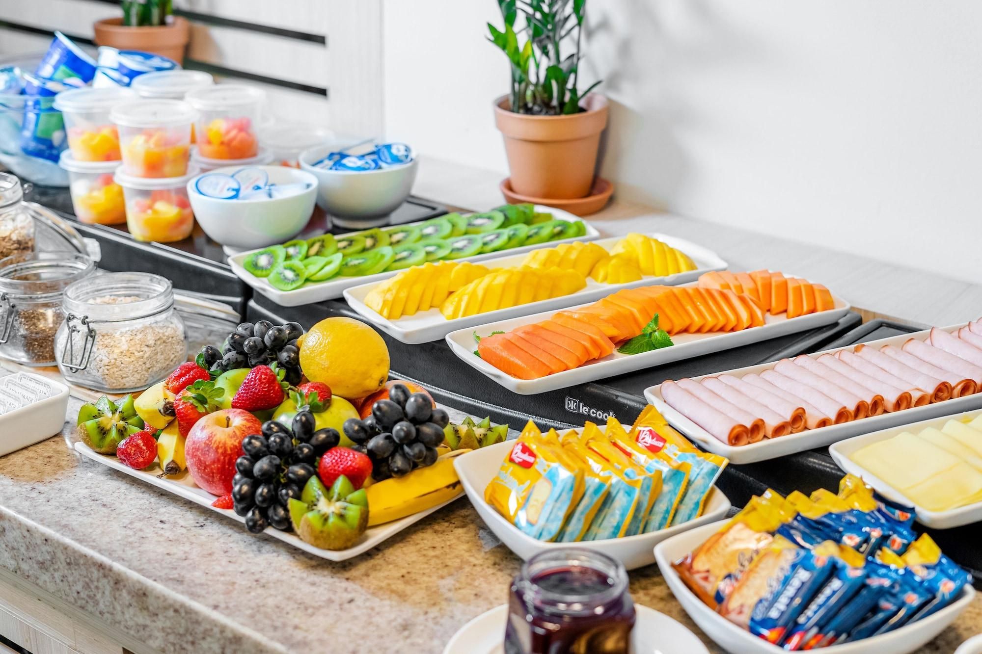 A buffet with various food items including fruits, vegetables, and packaged snacks.