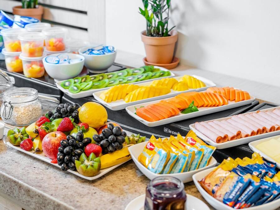 A buffet with various food items including fruits, vegetables, and packaged snacks.