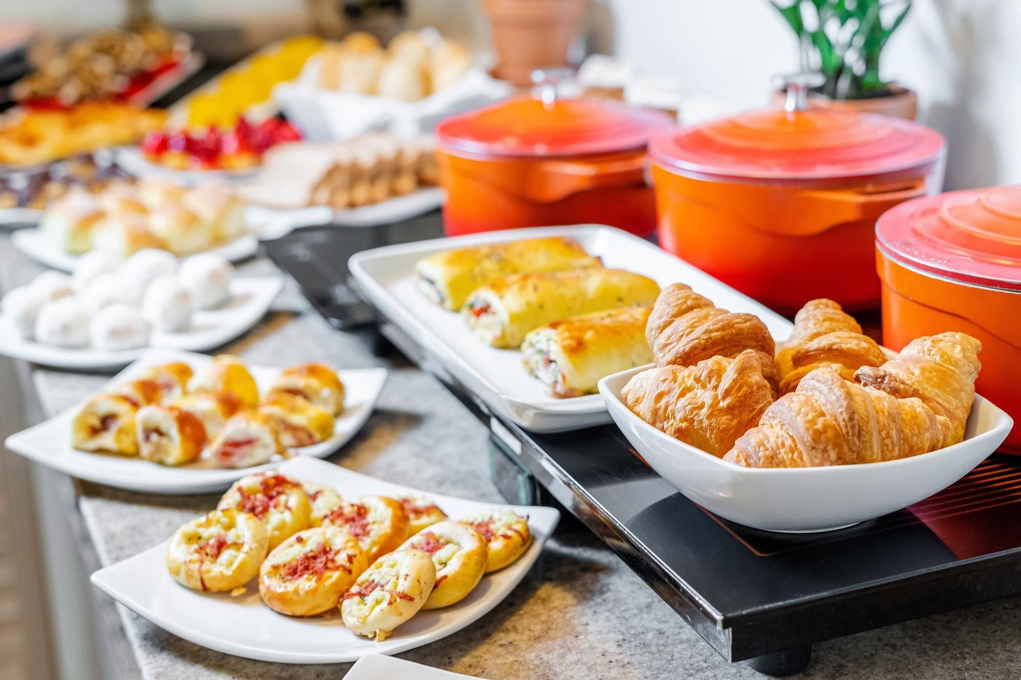 A buffet with various food items including pastries, rolls, and a selection of beverages.