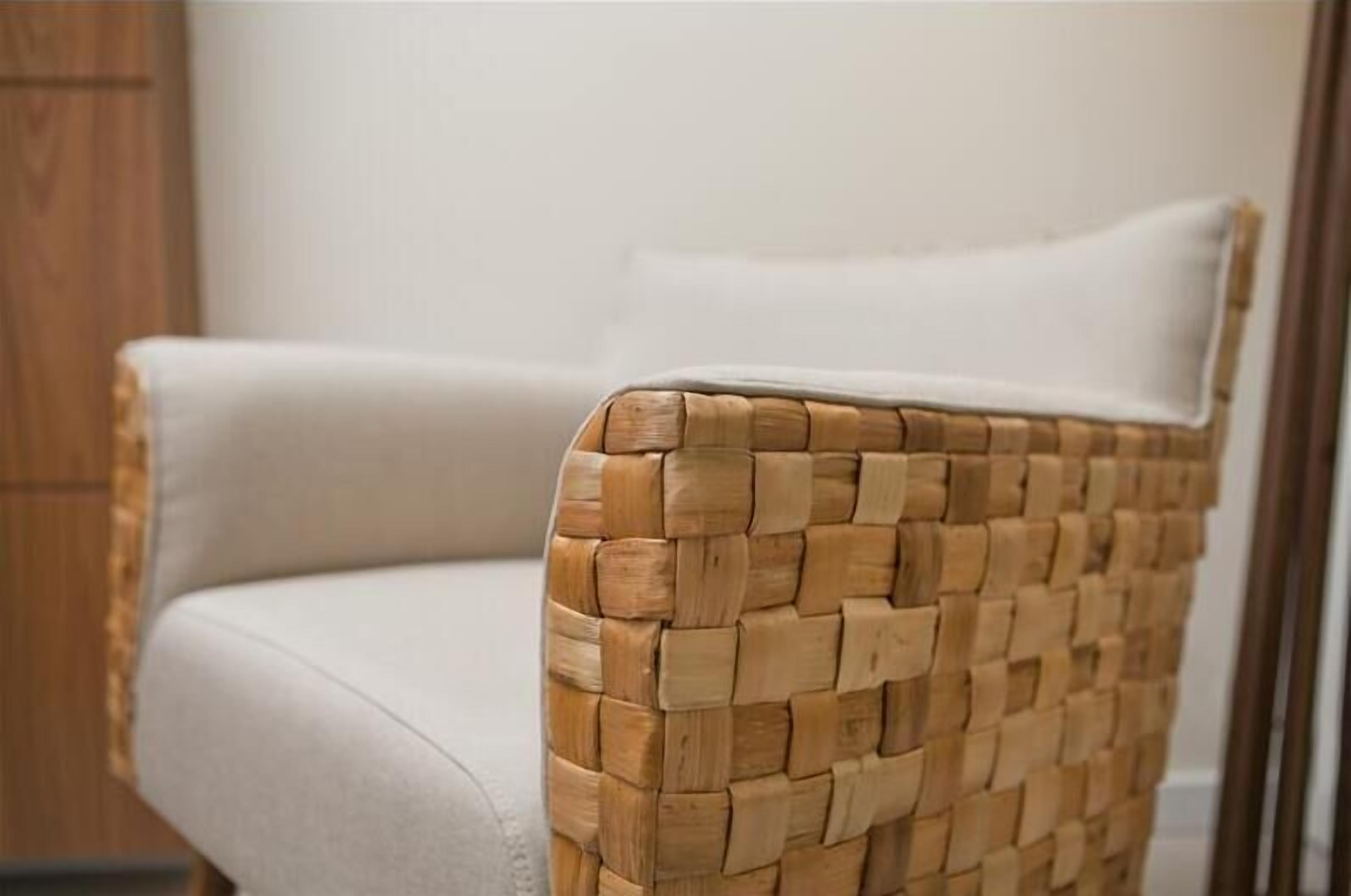 Une chaise en osier avec un coussin blanc.