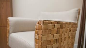 Une chaise en osier avec un coussin blanc.