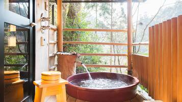 Eine Holzterrasse mit einem Whirlpool, einem Holzschemel und einem Holenzaun.