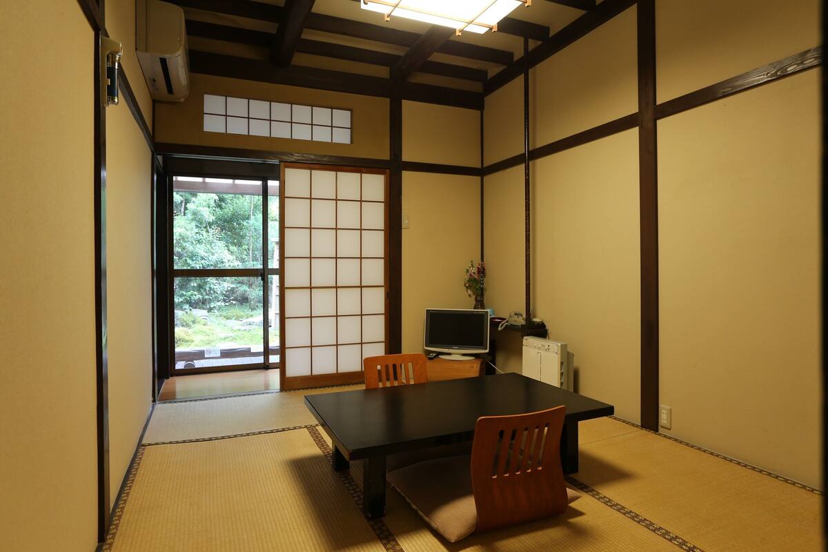 A traditional Japanese room with tatami flooring, a low table, and sliding doors.