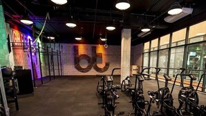 Un gimnasio con equipo de ejercicio, un muro de ladrillo con el número '6' grande y ventanas amplias.