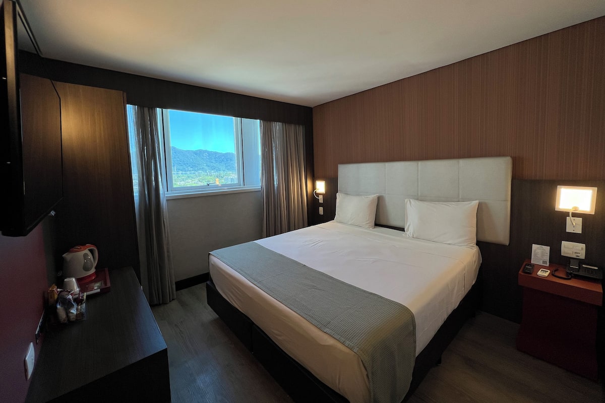 Una habitación de hotel con una cama grande, un escritorio con teléfono y una ventana con cortinas.
