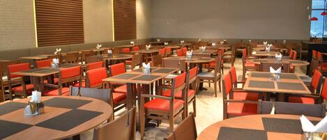 A spacious dining area with multiple tables and chairs, arranged in rows.