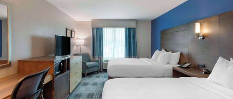 A hotel room with two beds, a desk, a chair, a TV, and a window with curtains.