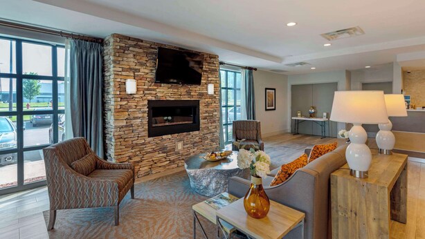 A modern living room with a stone fireplace, comfortable seating, a coffee table, and a view of the parking lot.