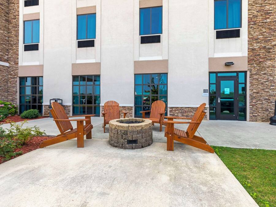 A building with a stone facade, large windows, and a fire pit with chairs in the center.