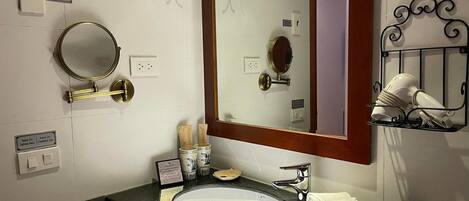 A bathroom with a white sink, a large mirror, a towel rack, and a towel on the counter.