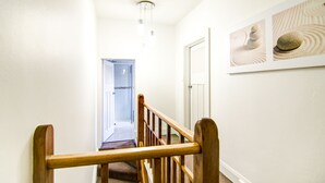 A hallway with a wooden railing, a door, and a framed picture on the wall. - Terrace on York (Launceston)