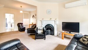 A living room with a fireplace, a television, and a sofa. - Terrace on Walbourne (Launceston)