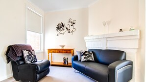 A living room with a black leather sofa, a wooden coffee table, and a decorative wall piece. - Terrace on Walbourne (Launceston)