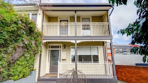 A two-story building with a balcony, a garage, and a brick wall. - Terrace on Walbourne (Launceston)