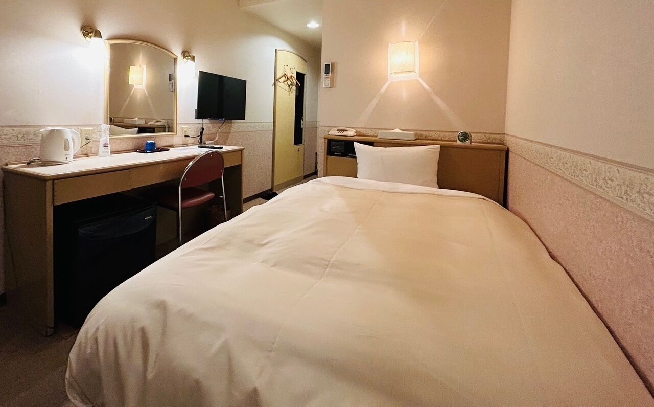 Une chambre d’hôtel équipée d’un lit, d’un bureau, d’une chaise et d’un téléviseur.