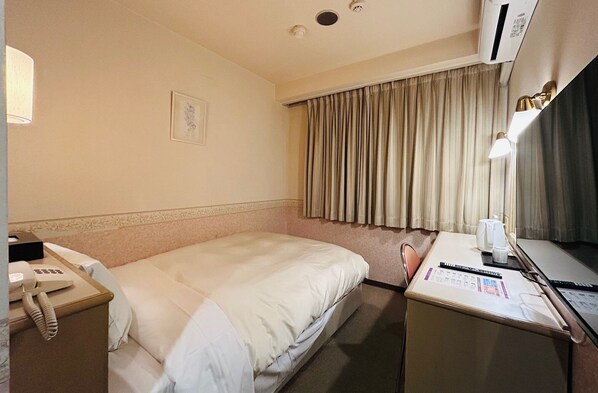 A hotel room with a bed, a desk with a computer, a telephone, and a window with curtains. - Crown Hills Kanazawa (Kanazawa)