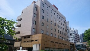Un hôtel à plusieurs étages doté d’une architecture moderne, caractérisé par un mélange de façades en brique et en béton, de nombreux balcons et une enseigne bien visible indiquant son nom.