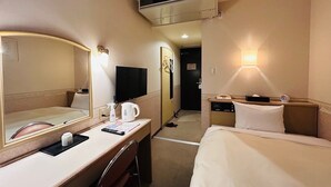 Une chambre d’hôtel comprenant un lit, un bureau avec un miroir, une télévision et un luminaire fixé au mur.