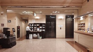 Un hall d’hôtel comprenant un comptoir d’accueil, une machine à café et un présentoir à chaussures.