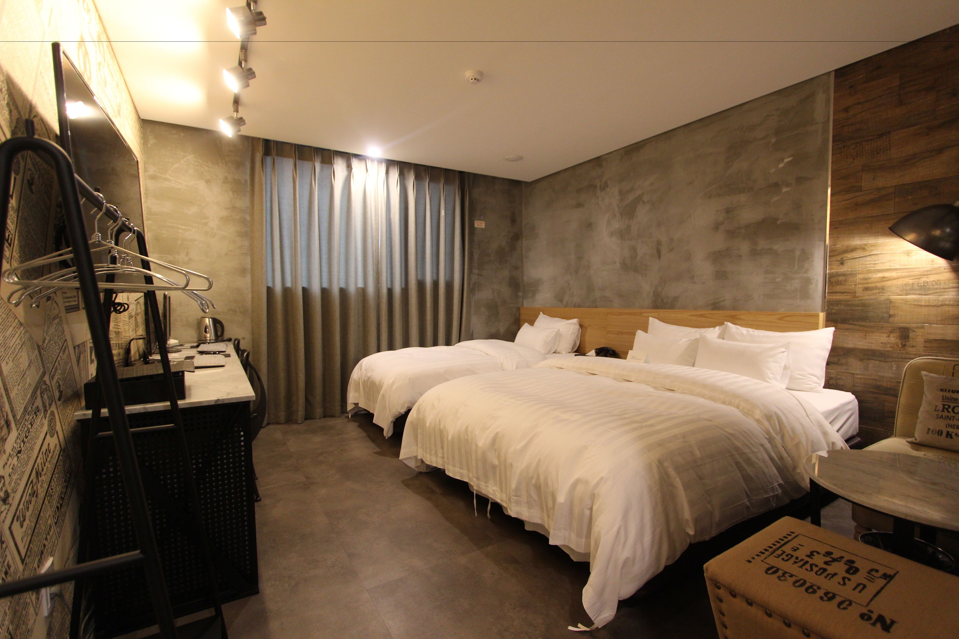 A hotel room with two beds, a desk, and a chair.