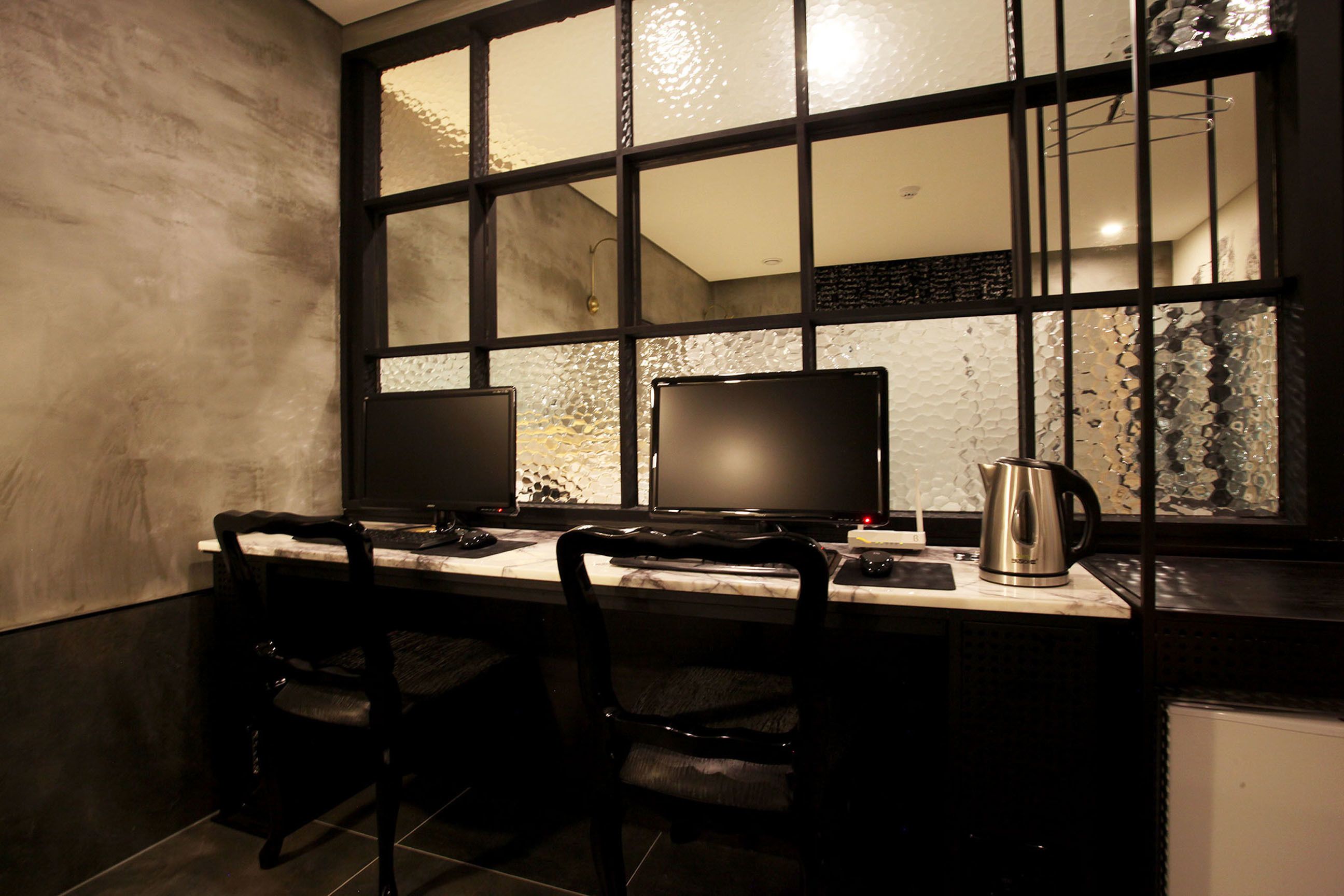 A modern kitchen with two black chairs, a marble countertop, and a large window with a textured view.