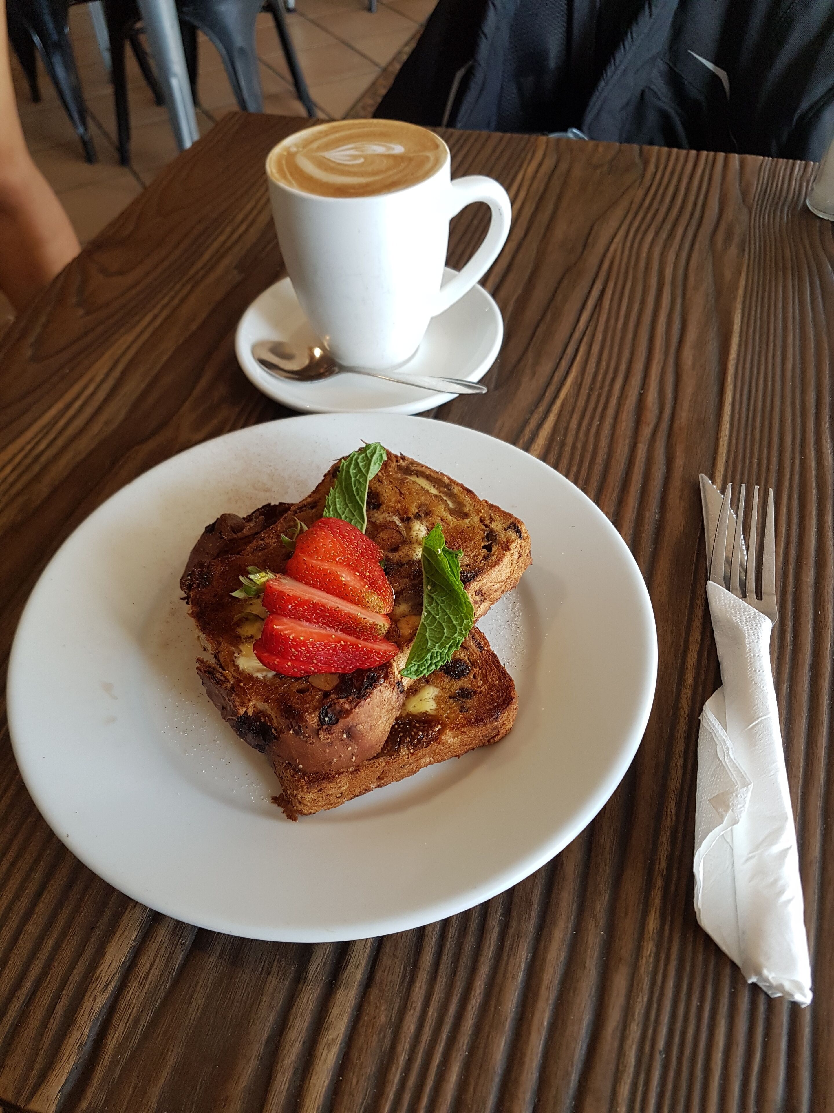 Un piatto di pane tostato con fragole e menta su un tavolo di legno.