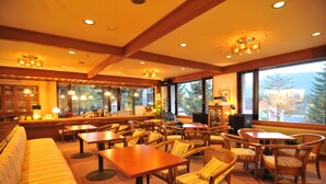 A cozy restaurant with wooden furniture, large windows, and a view of the outdoors.