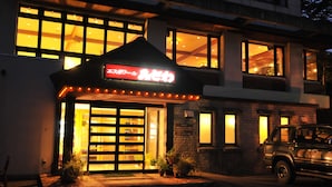 A building with illuminated signage and a car parked in front.
