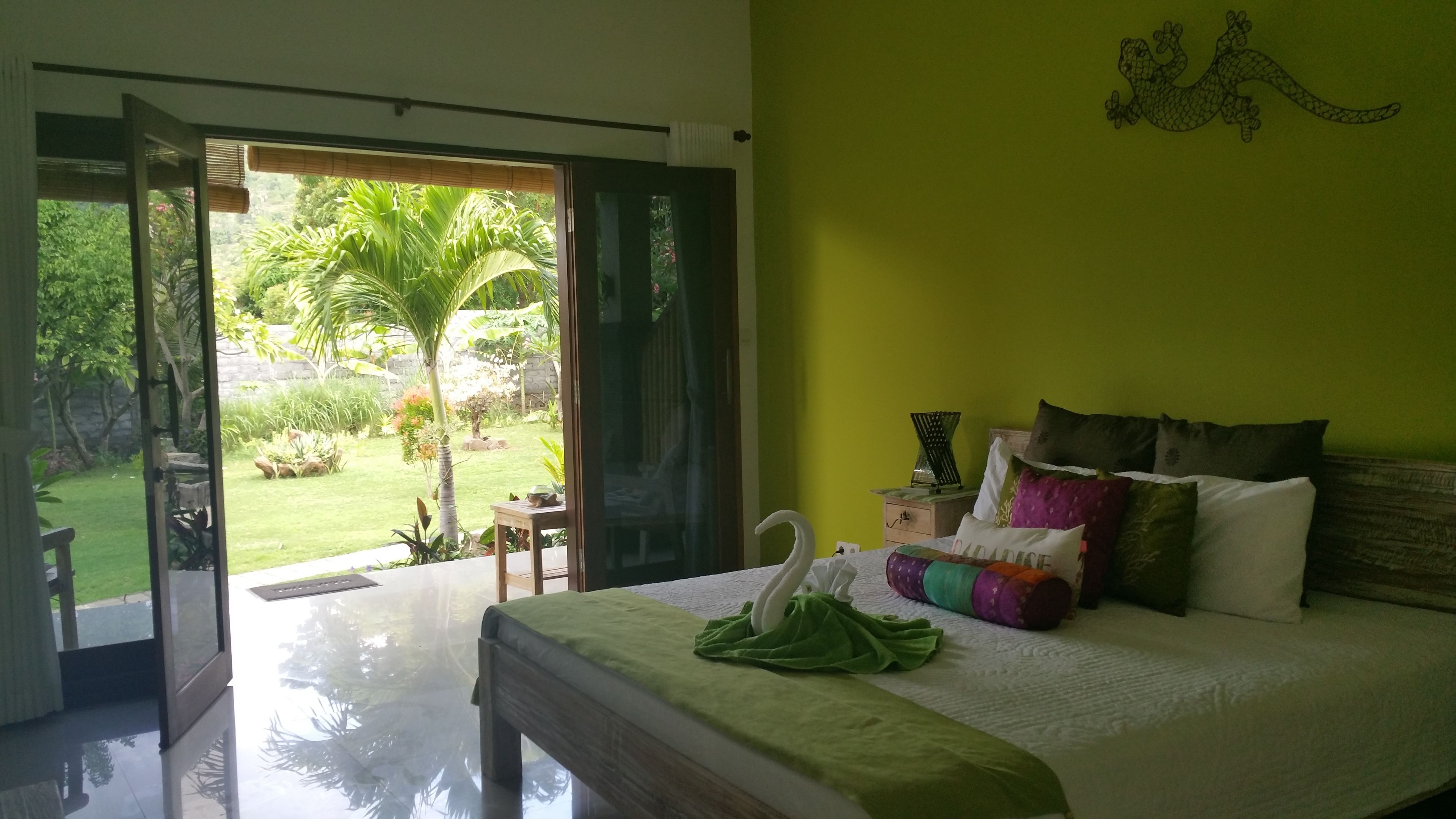 A bedroom with a bed, pillows, and a green wall.